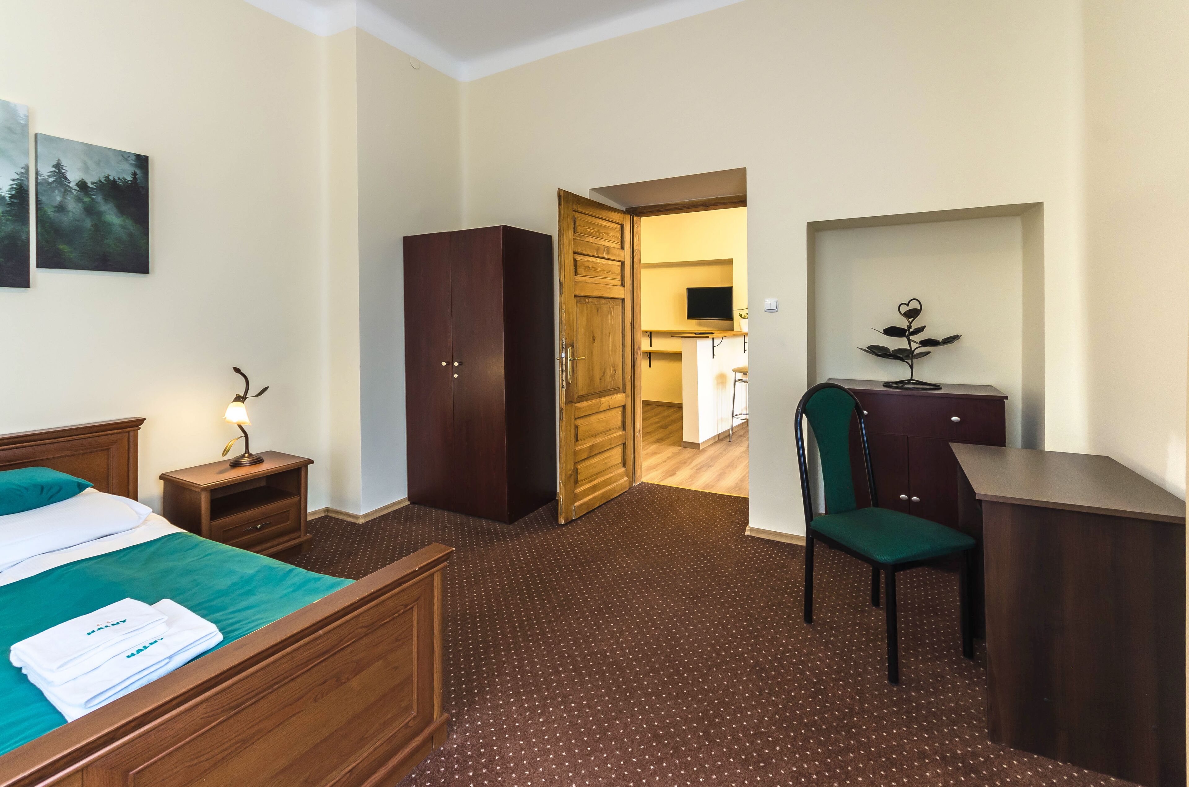 Une chambre d’hôtel comprenant un lit, un bureau, une chaise, une armoire et un téléviseur.