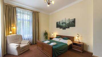 Une chambre d’hôtel avec un lit, une chaise, une table de chevet, une lampe et un tableau au mur.