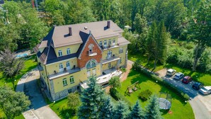 A multi-story building with a prominent red brick section, large windows, and a balcony. - Pensjonat Halny (Zakopane)