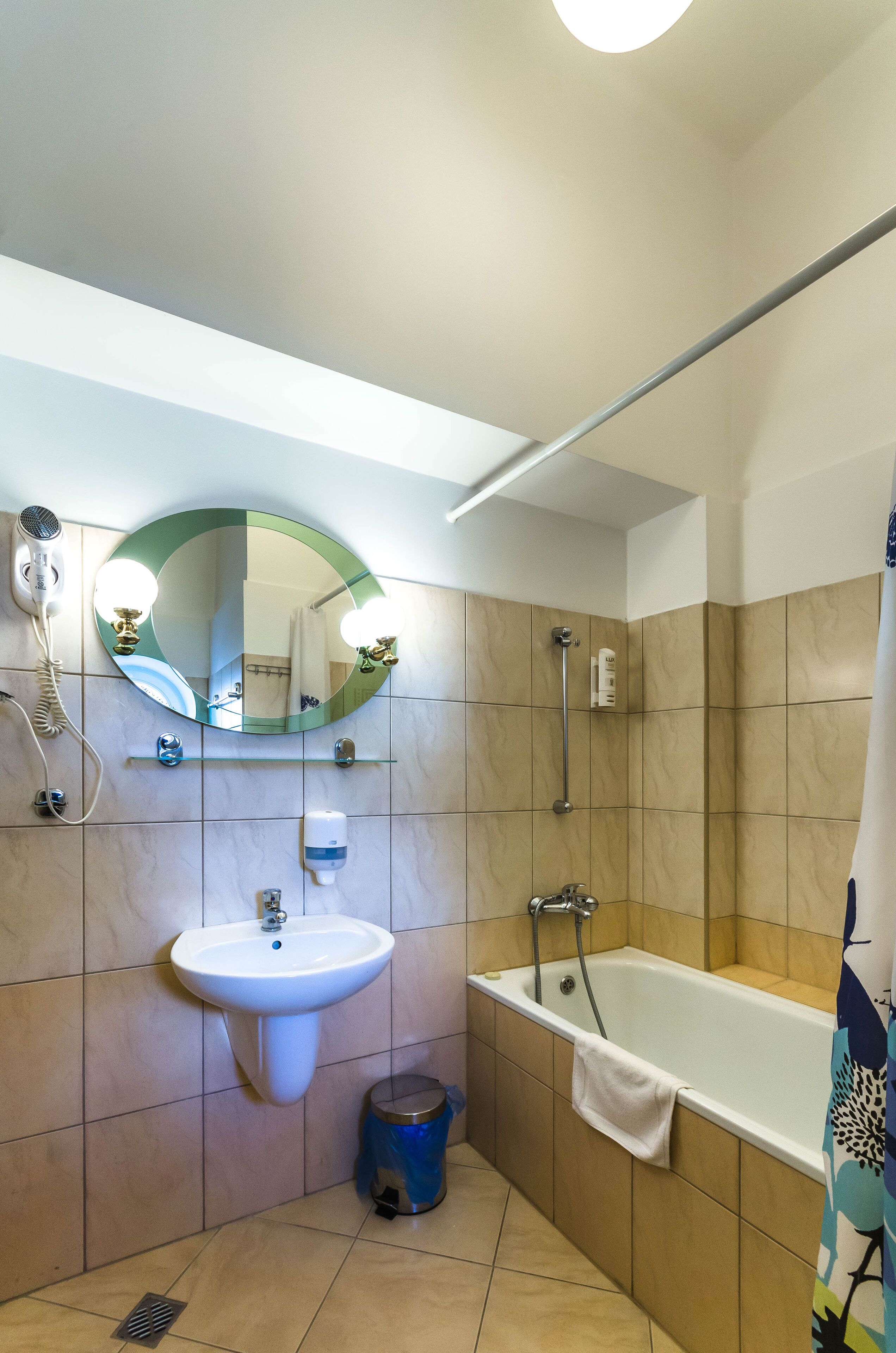 A bathroom with a sink, mirror, and bathtub.
