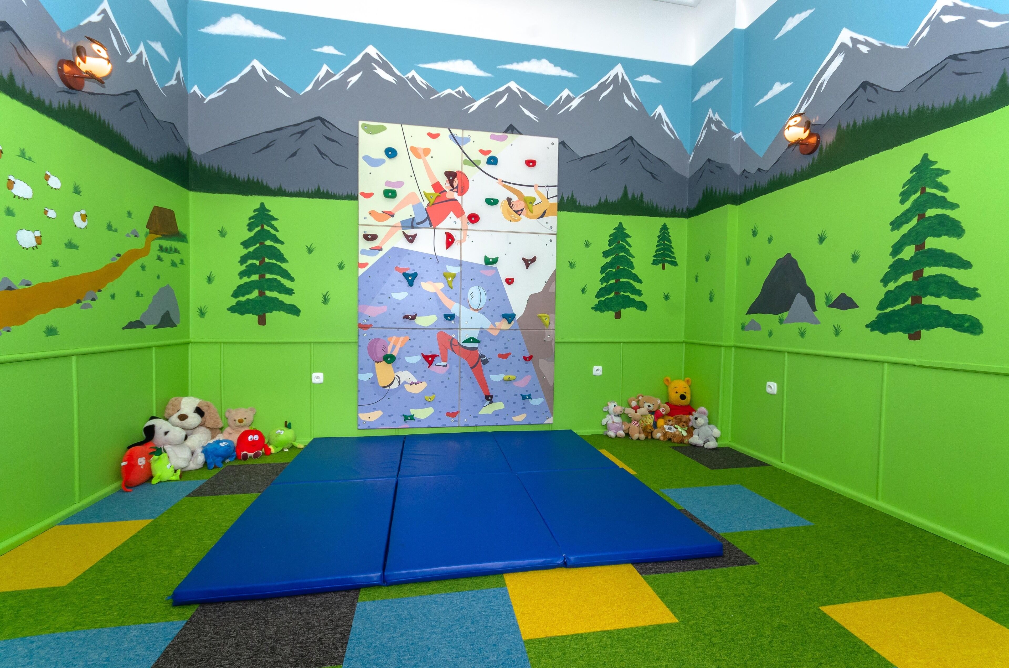 Uma sala de jogos infantil com uma parede de escalada, tapetes coloridos e brinquedos de pelúcia.