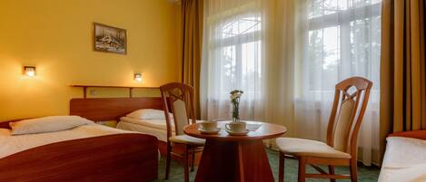 Una habitación de hotel con dos camas, una mesa de comedor con sillas y un cuadro en la pared.