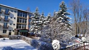A building with a reception area, snow-covered trees, and a clear blue sky. - Pensjonat Halny (Zakopane)