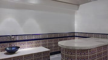 Bathroom features a geometric-patterned backsplash, a white sink, and a small bench.