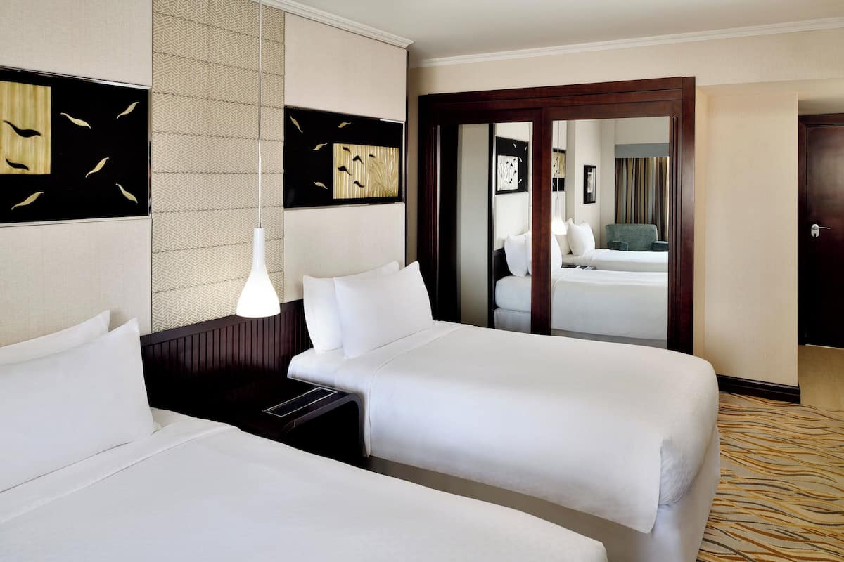 A hotel room with two beds, a large mirror, and a patterned carpet.