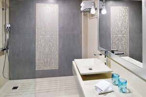 A modern bathroom with a large mirror, a sink, and a shower area.