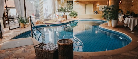 Una piscina cubierta, una piscina al aire libre, tumbonas