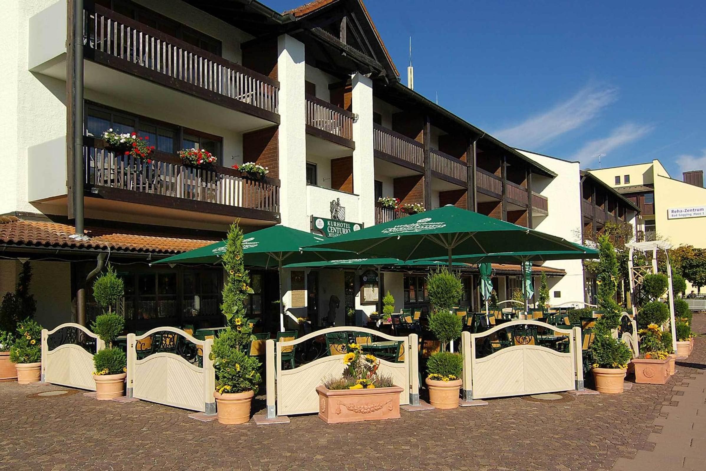 Un hotel con mobiliario exterior, varios balcones y plantas en macetas.