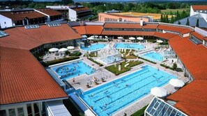 A swimming pool complex with multiple pools and a covered area, surrounded by buildings with red-tiled roofs. - Hotel Centurio (Neustadt an der Donau)
