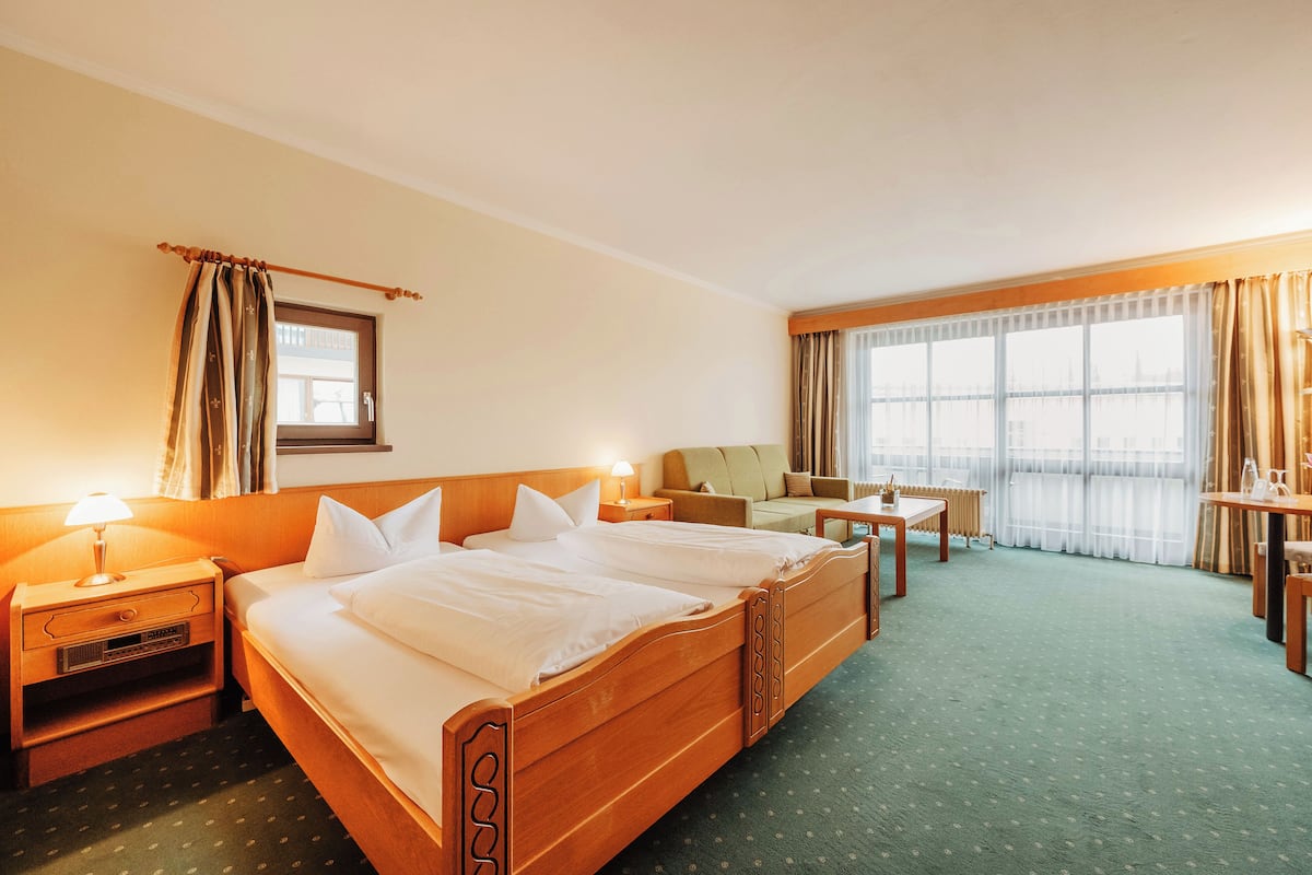 A hotel room with a large bed, a desk, a chair, and a sofa.