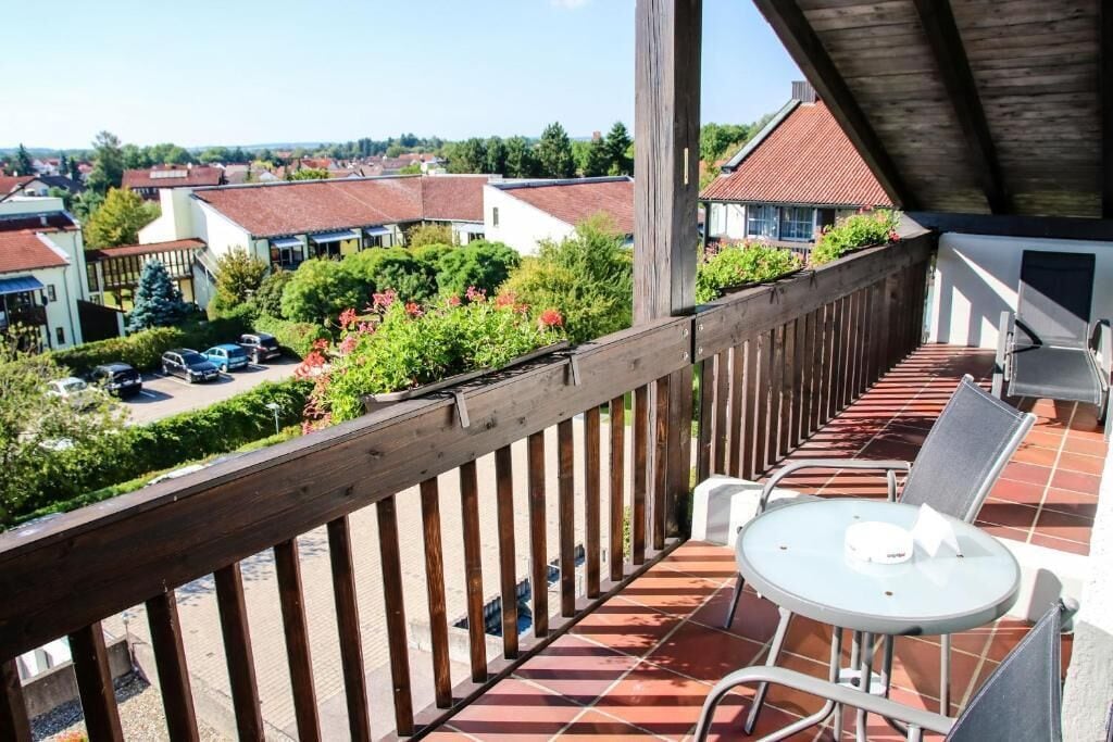 Un balcón con vistas a una zona residencial, una mesa con sillas y una sección cubierta.