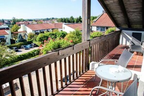 A balcony with a view of a residential area, a table with chairs, and a covered section. - Hotel Centurio (Neustadt an der Donau)