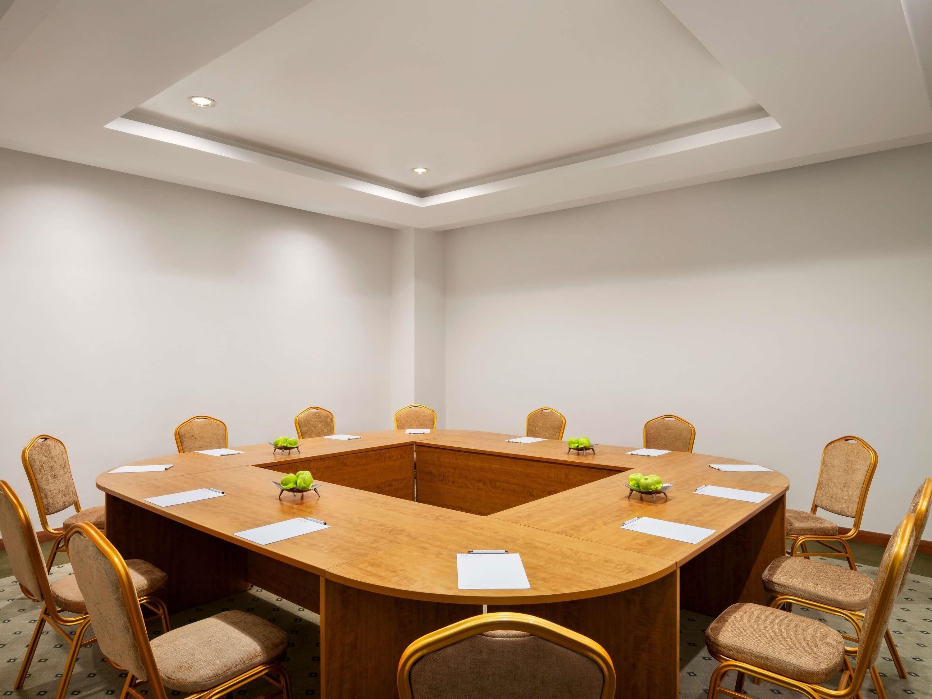 Ein Konferenzraum mit rundem Tisch, acht Stühlen und einer Deckeneinbauleuchte.