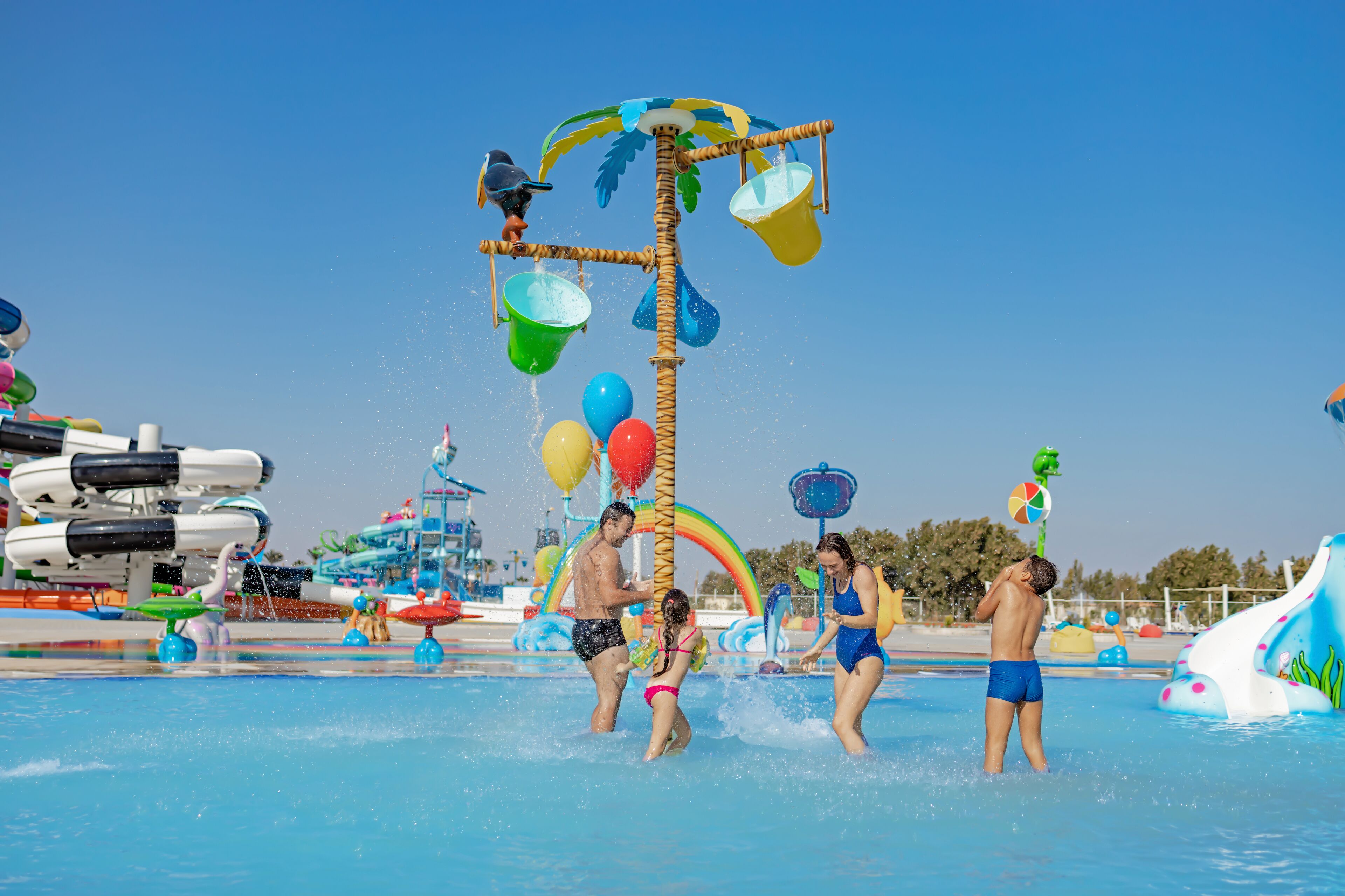 A water park with a central water feature, inflatable slides, and various play structures.