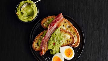 Une assiette avec des toasts à l’avocat, du bacon et deux moitiés d’œuf dur.