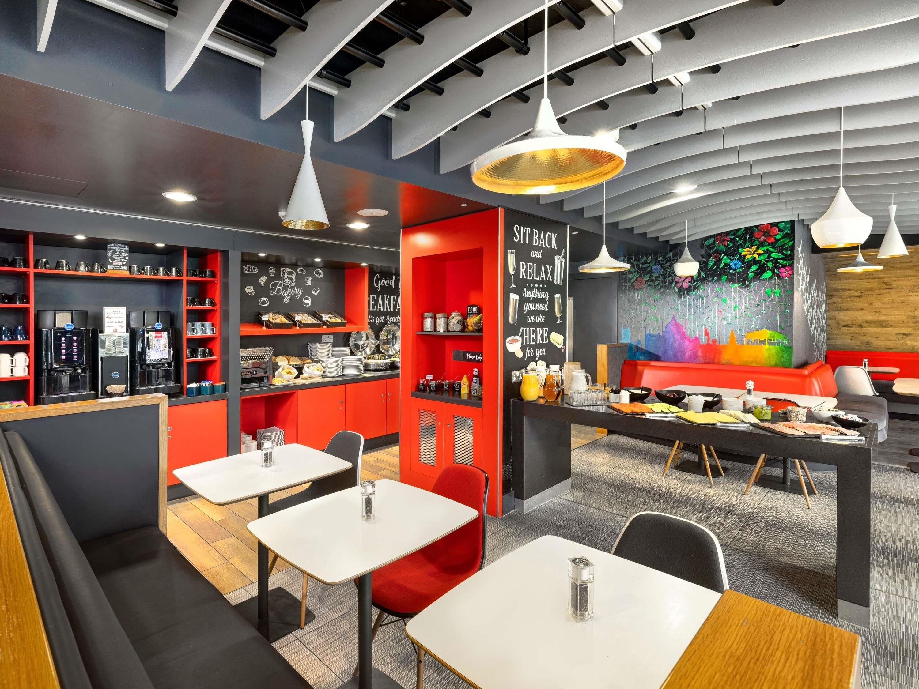 A modern cafe with seating, coffee machines, and a colorful mural.