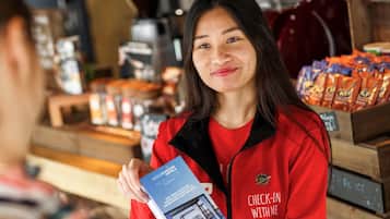 A person holding a brochure in a room with a wooden counter displaying snacks and a coffee machine.