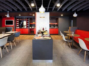Un espace repas moderne avec des banquettes, des tables rondes et un îlot central pour le service.