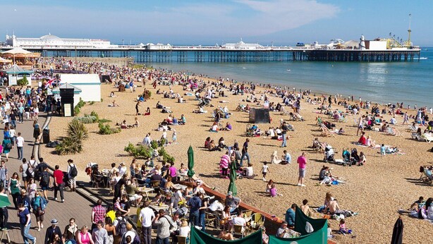 A crowded beach with people sunbathing and walking.