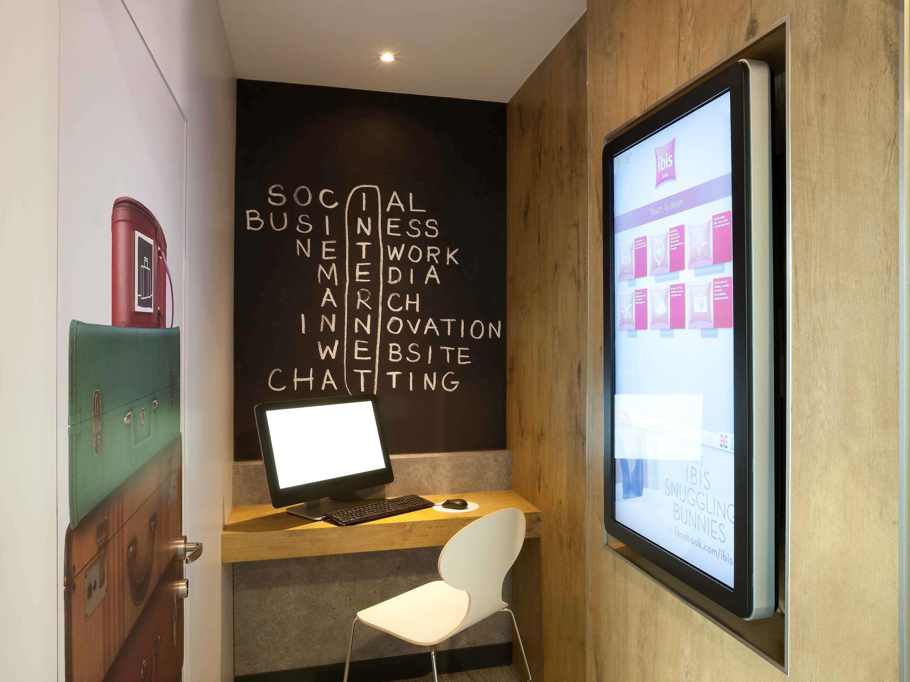 A modern office space with a desk, computer, and a wall displaying various business-related words.