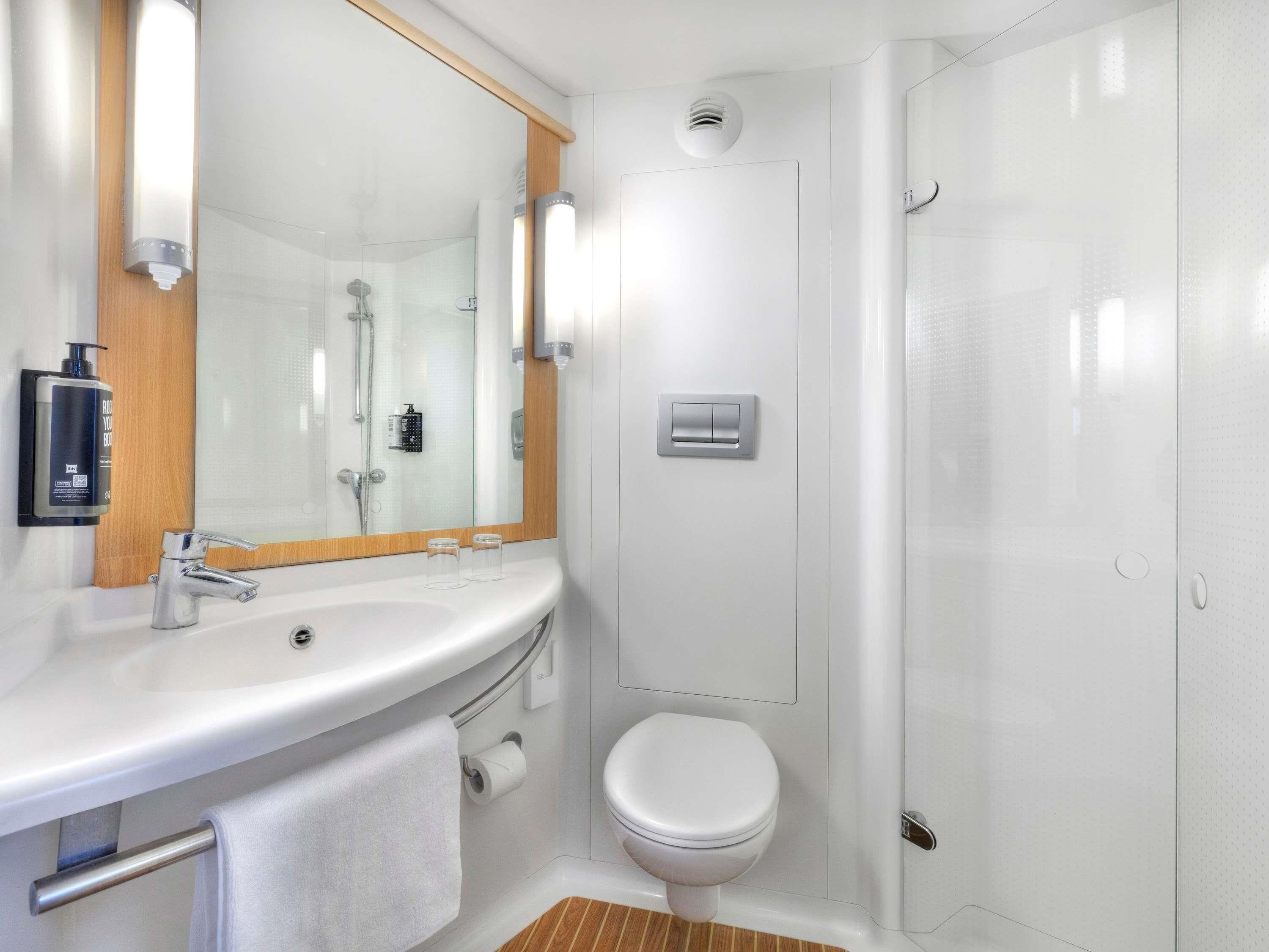 A modern bathroom with a sink, mirror, toilet, and shower.
