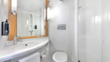 A modern bathroom with a sink, mirror, toilet, and shower.