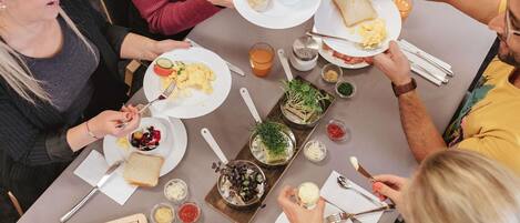 A group of people dining at a table with various dishes, utensils, and condiments.
