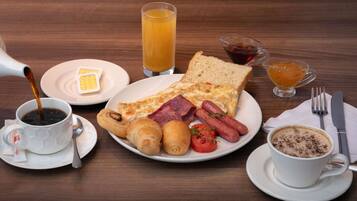 A breakfast setting with a variety of food items including toast, eggs, sausages, and pastries, along with beverages and condiments.