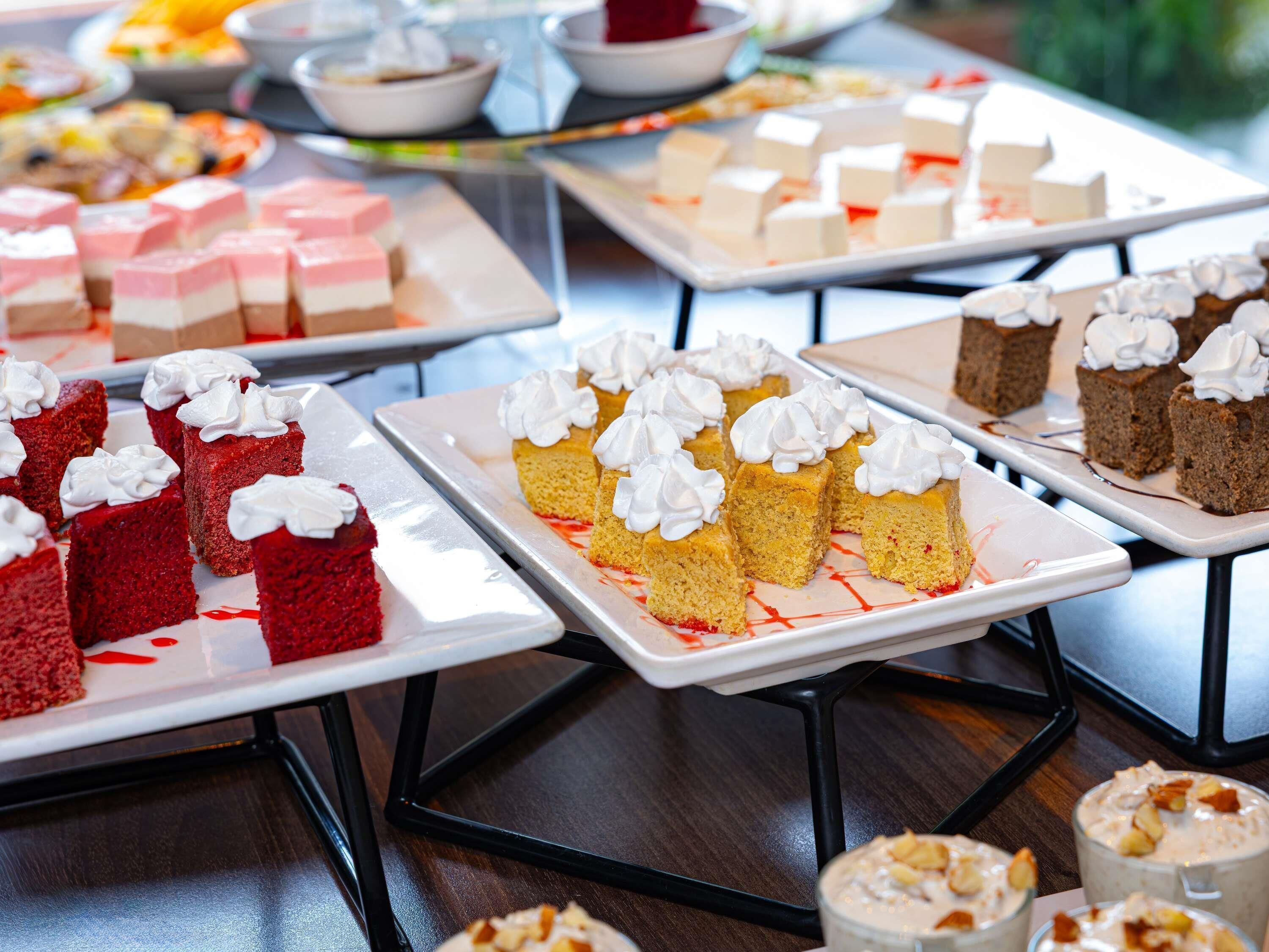 A variety of desserts on trays, including cakes and pastries, displayed on a table.