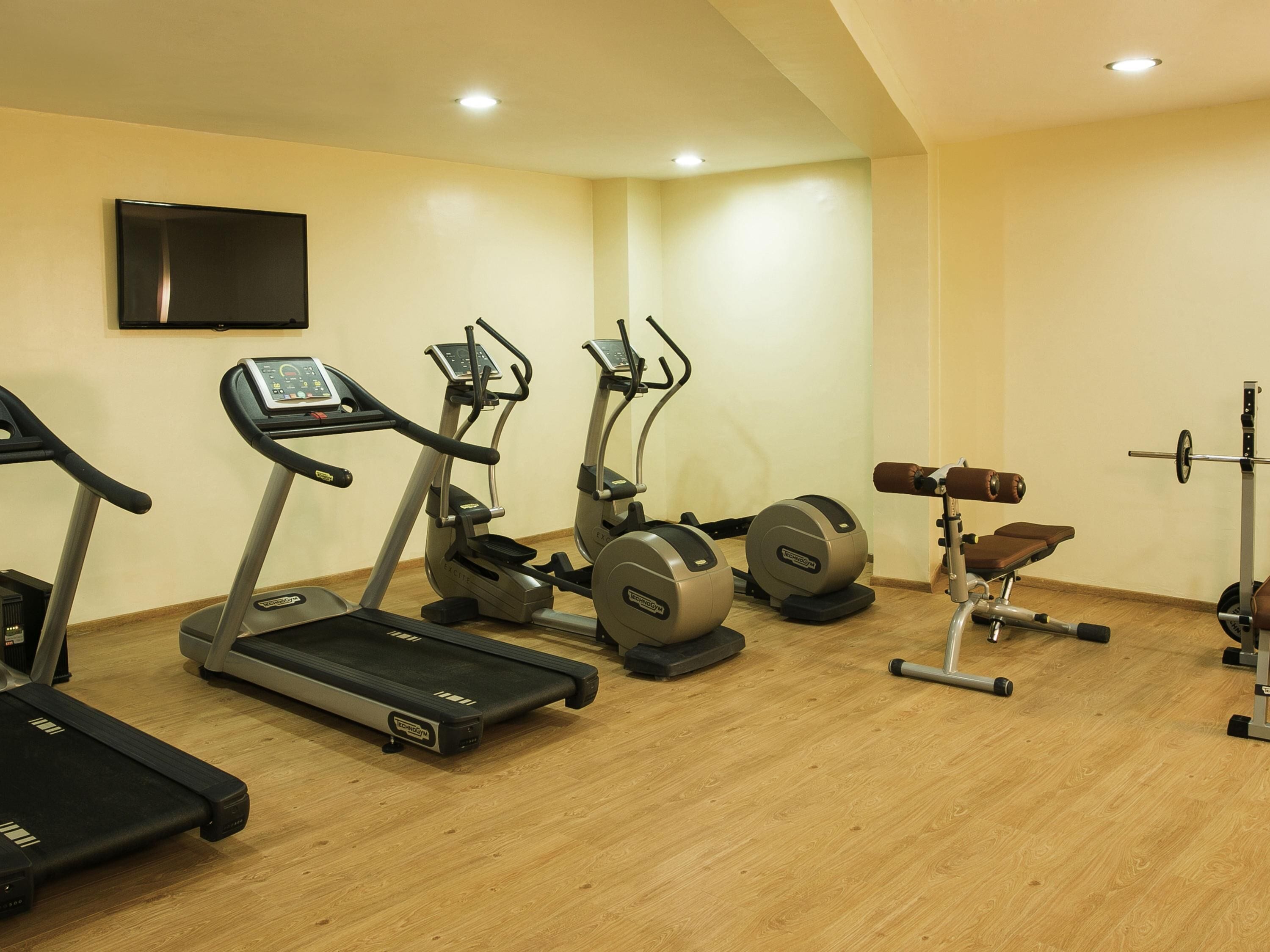 Ein Fitnessstudio mit Laufbändern, Crosstrainern und Gewichten.