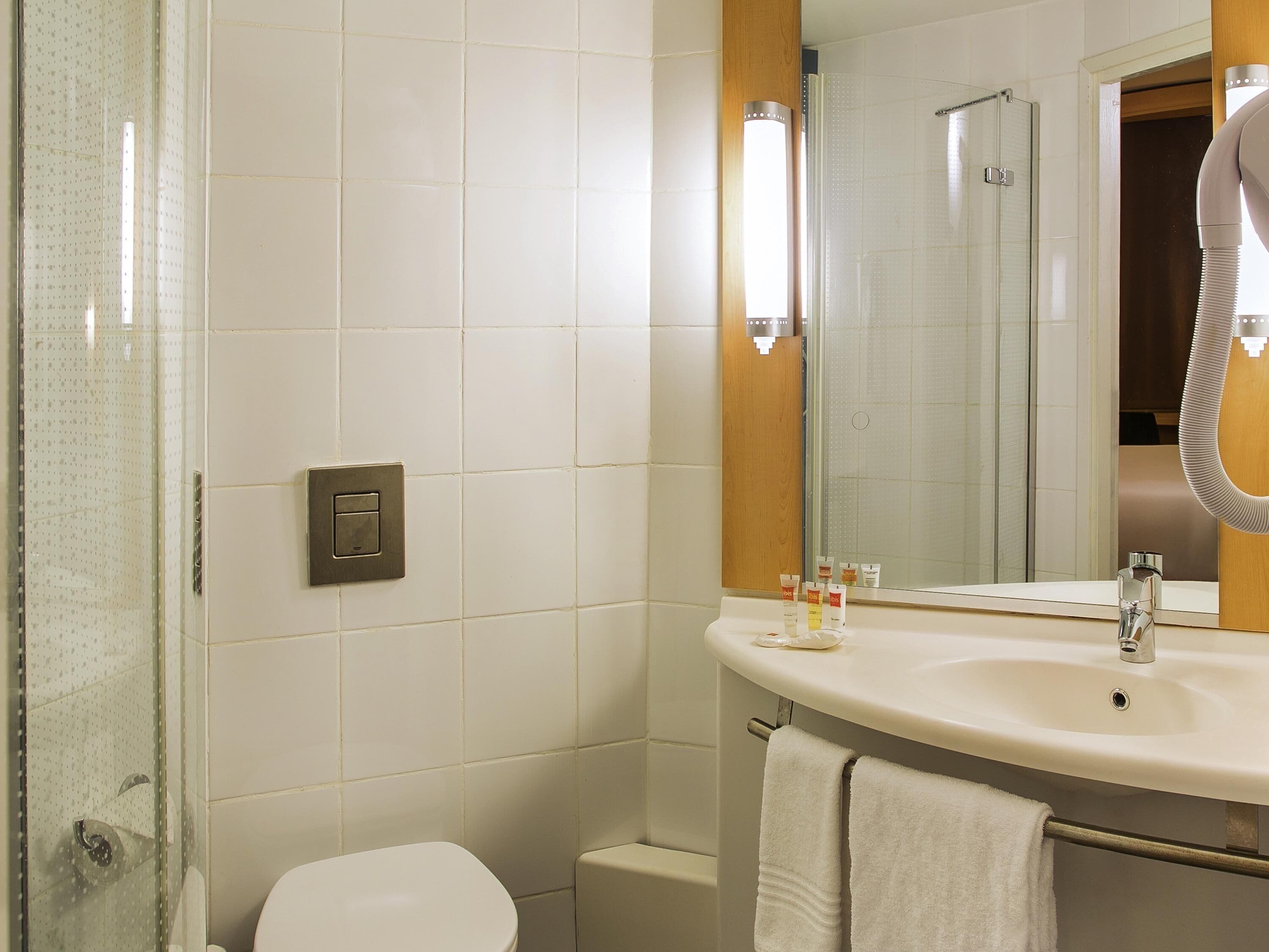 A bathroom with a white toilet, a sink with a mirror, and a shower area.