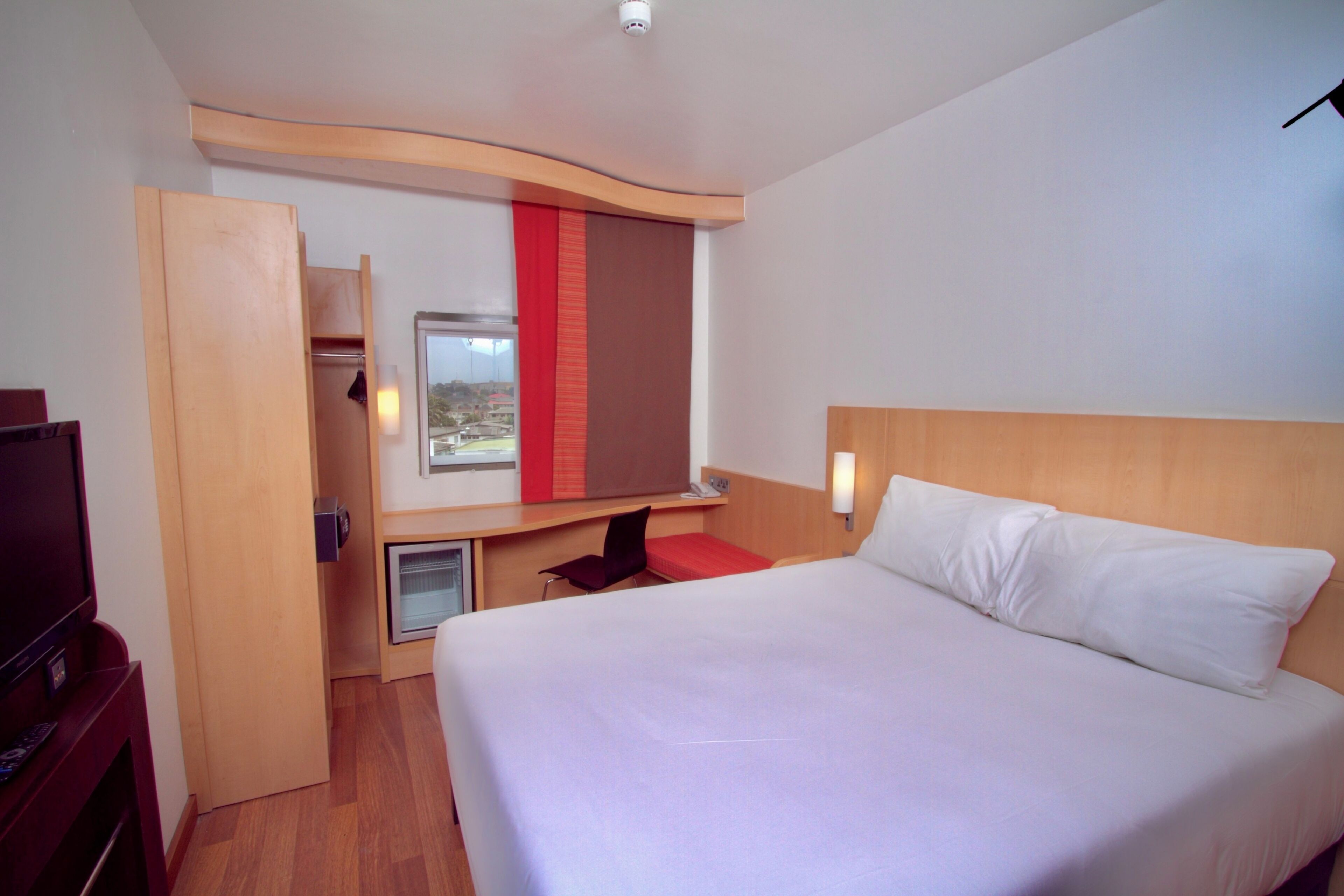 Camera d'albergo con un letto, una scrivania, una TV e una finestra vista.
