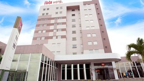 A modern hotel building with a prominent 'ibis HOTEL' sign, large windows, and a paved entrance area. - Ibis Feira De Santana (Feira de Santana)
