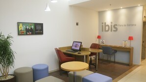 A reception area with a computer, seating, and a wall-mounted sign. - Ibis Feira De Santana (Feira de Santana)