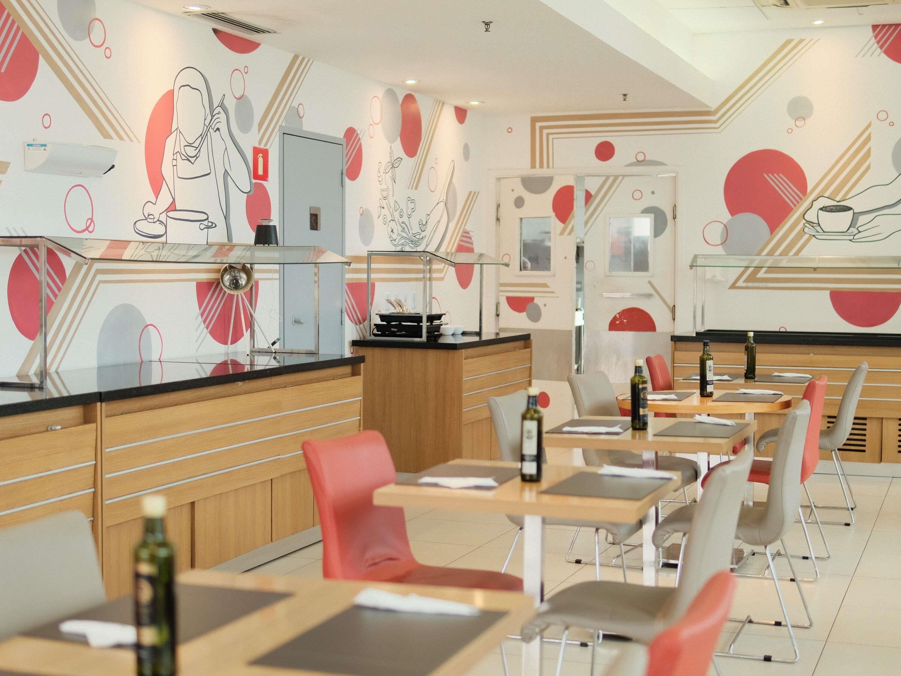 A modern restaurant interior with a counter, seating area, and abstract wall art.
