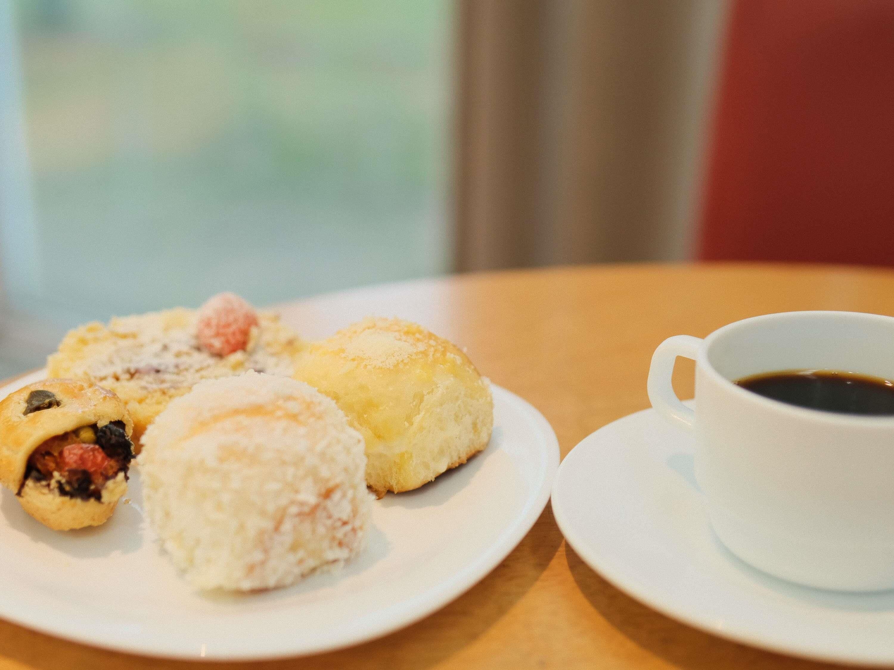 Um prato com diversos doces e uma xícara de café sobre uma mesa.