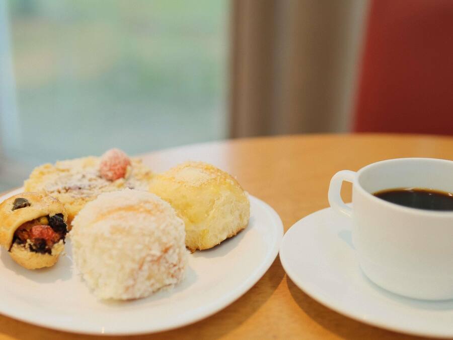 Um prato com diversos doces e uma xícara de café sobre uma mesa.