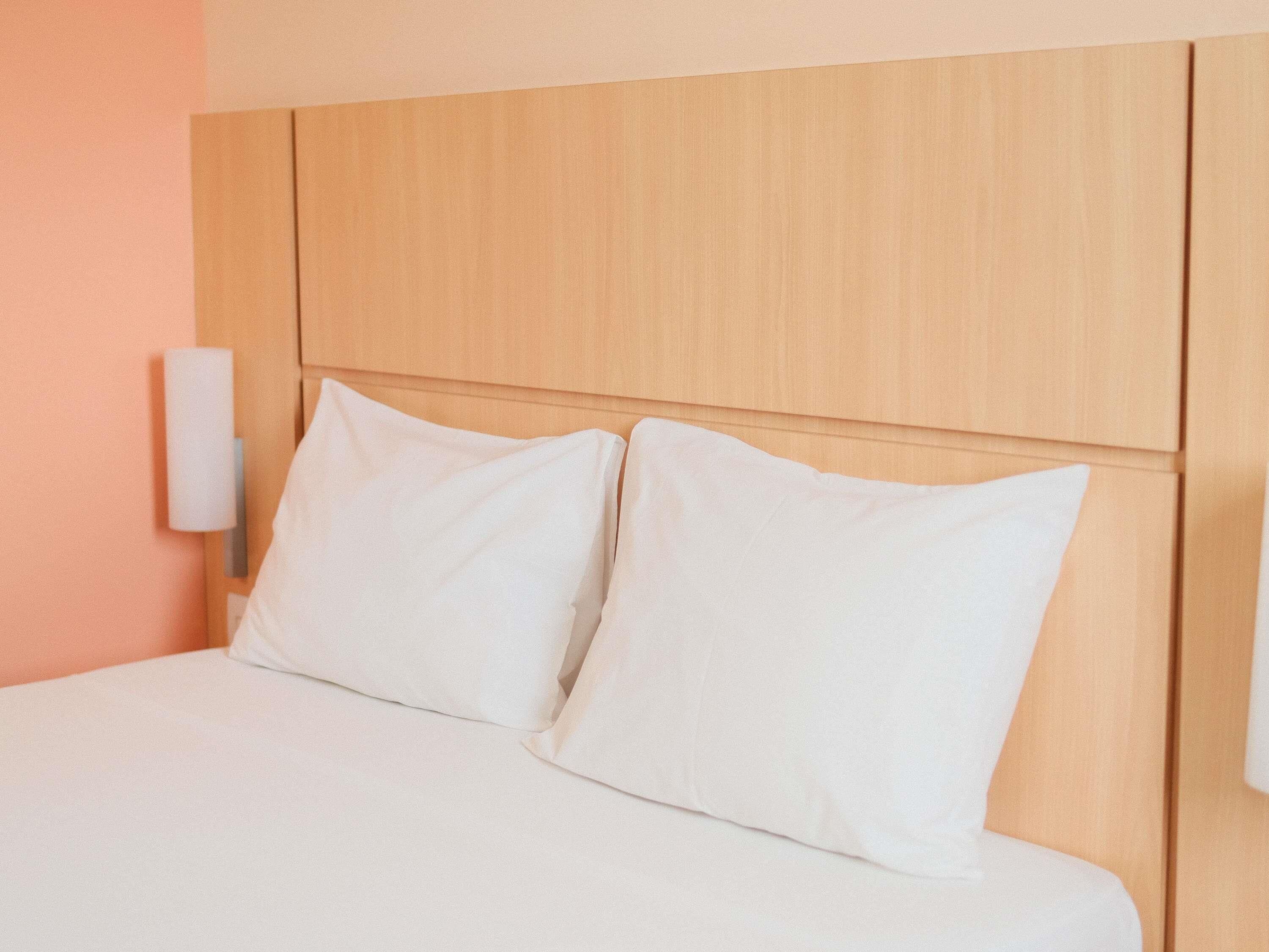 Una cama con ropa de cama blanca y un cabecero de madera.