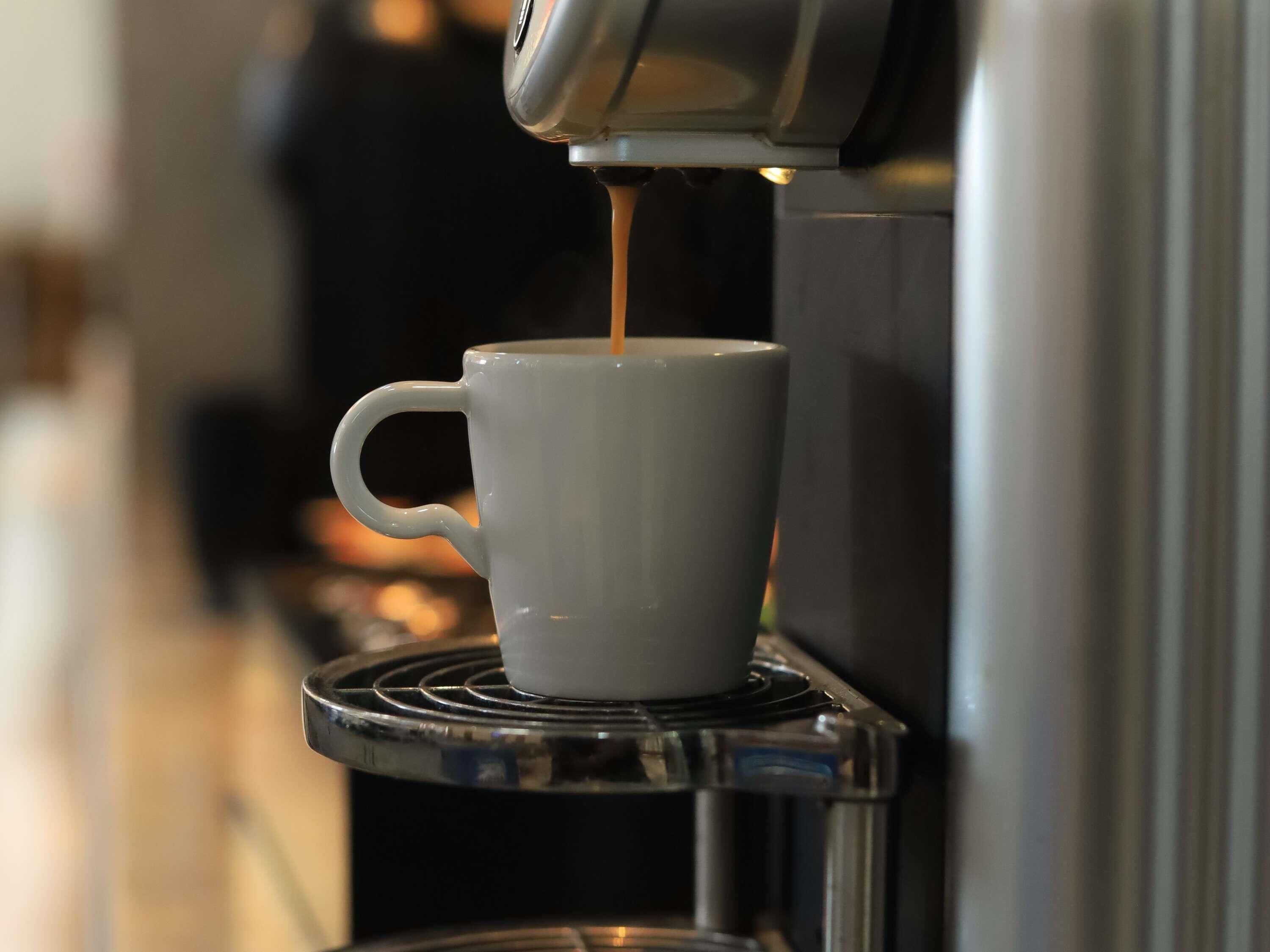 A coffee machine dispensing coffee into a white cup.