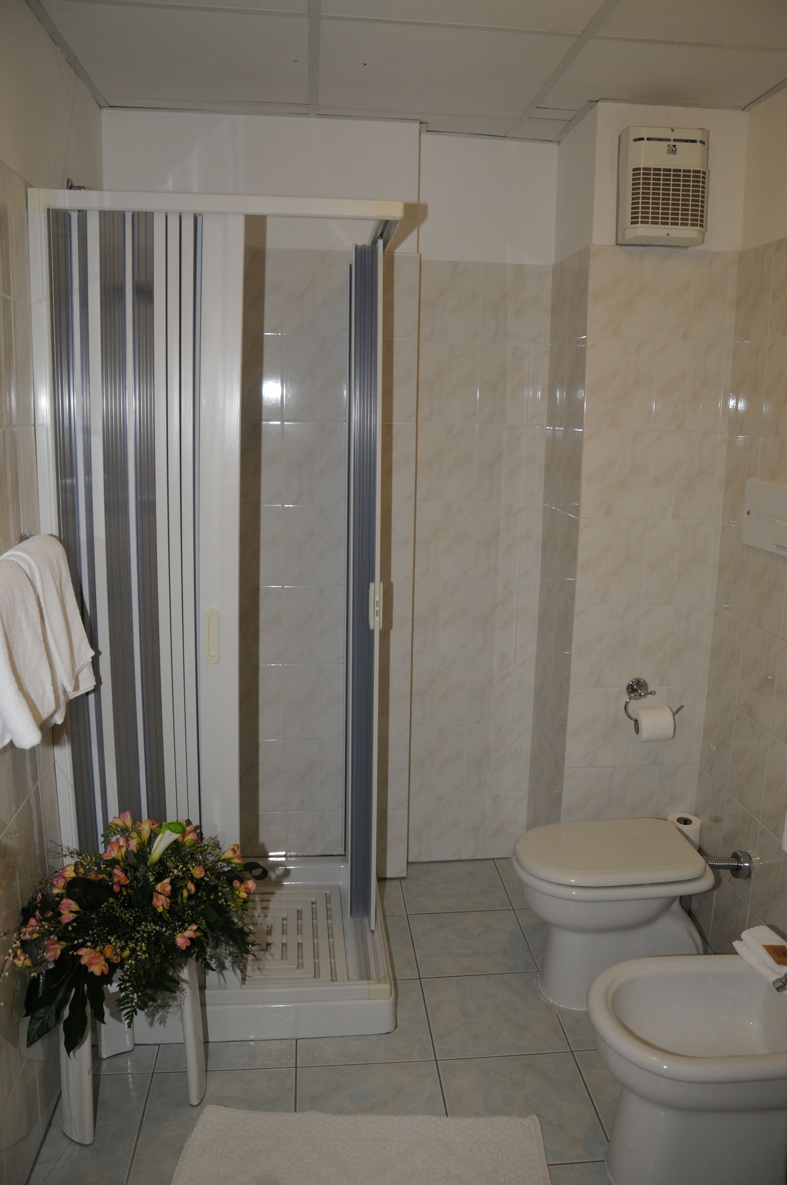A bathroom with a shower enclosure, toilet, and a towel rack with a towel.