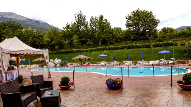 Un espace aménagé au bord de la piscine, avec des chaises longues, des parasols et un auvent.
