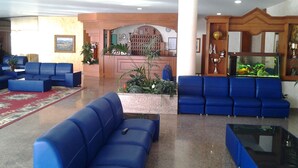 En lobby med blå sofaer, en receptionsdisk, et stort akvarium og et rødt tæppe.