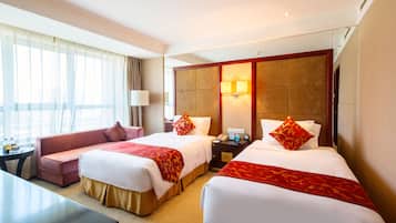 Habitación de hotel con dos camas, un sofá, un escritorio y un amplio ventanal con cortinas.