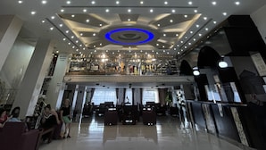 A modern hotel lobby with a large geometric ceiling design, a central blue-lit circular feature, and a seating area with sofas and a coffee table. - Ararat Hotel (Bethlehem)