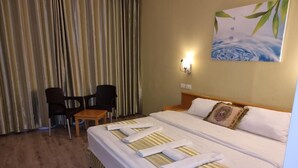 A hotel room with a bed, a chair, a table, and a painting on the wall. - Ararat Hotel (Bethlehem)