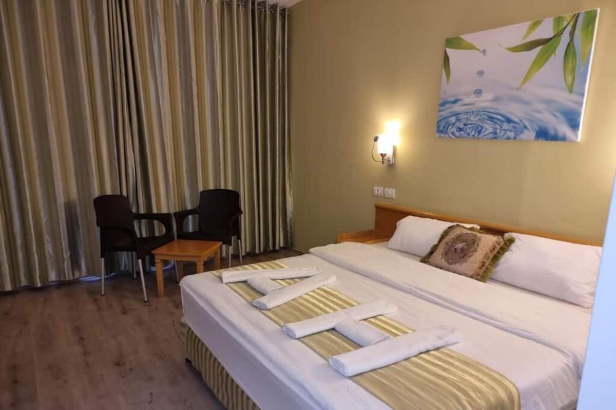 Une chambre d’hôtel avec un lit, une chaise, une table et un tableau au mur.
