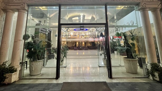 A hotel entrance with a glass facade, a central doorway, and a tiled floor. - Ararat Hotel (Bethlehem)