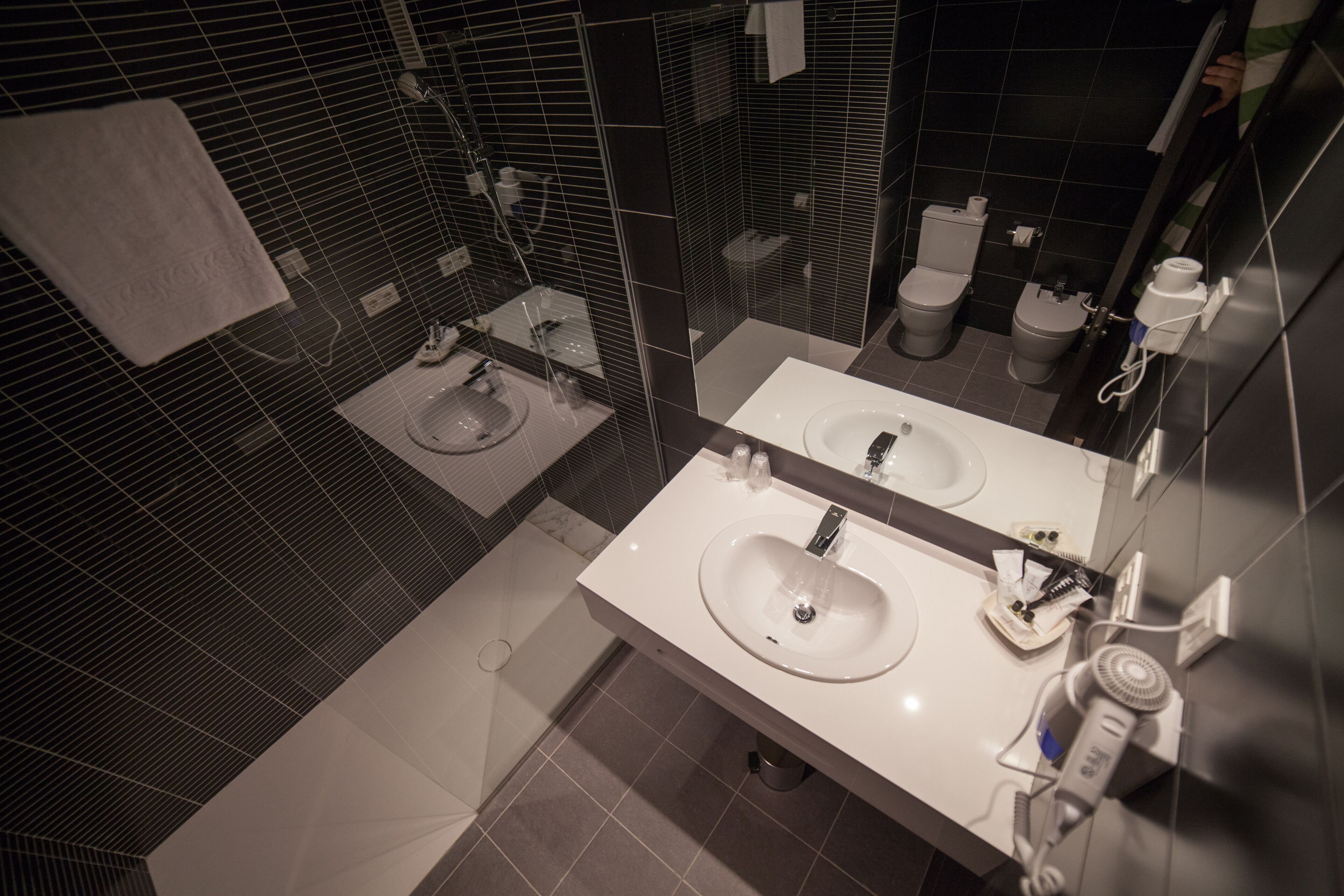 A modern bathroom with two sinks, a shower, and a toilet.