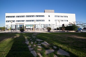 Un edificio moderno con techo plano, varias ventanas y un letrero con una 'H'.