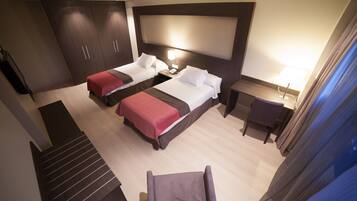 Habitación de hotel con dos camas, un escritorio, una silla y una escalera.